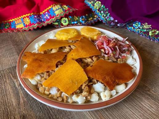 Plato de cascaritas con mote, curtido de cebolla y tomate, y tostado